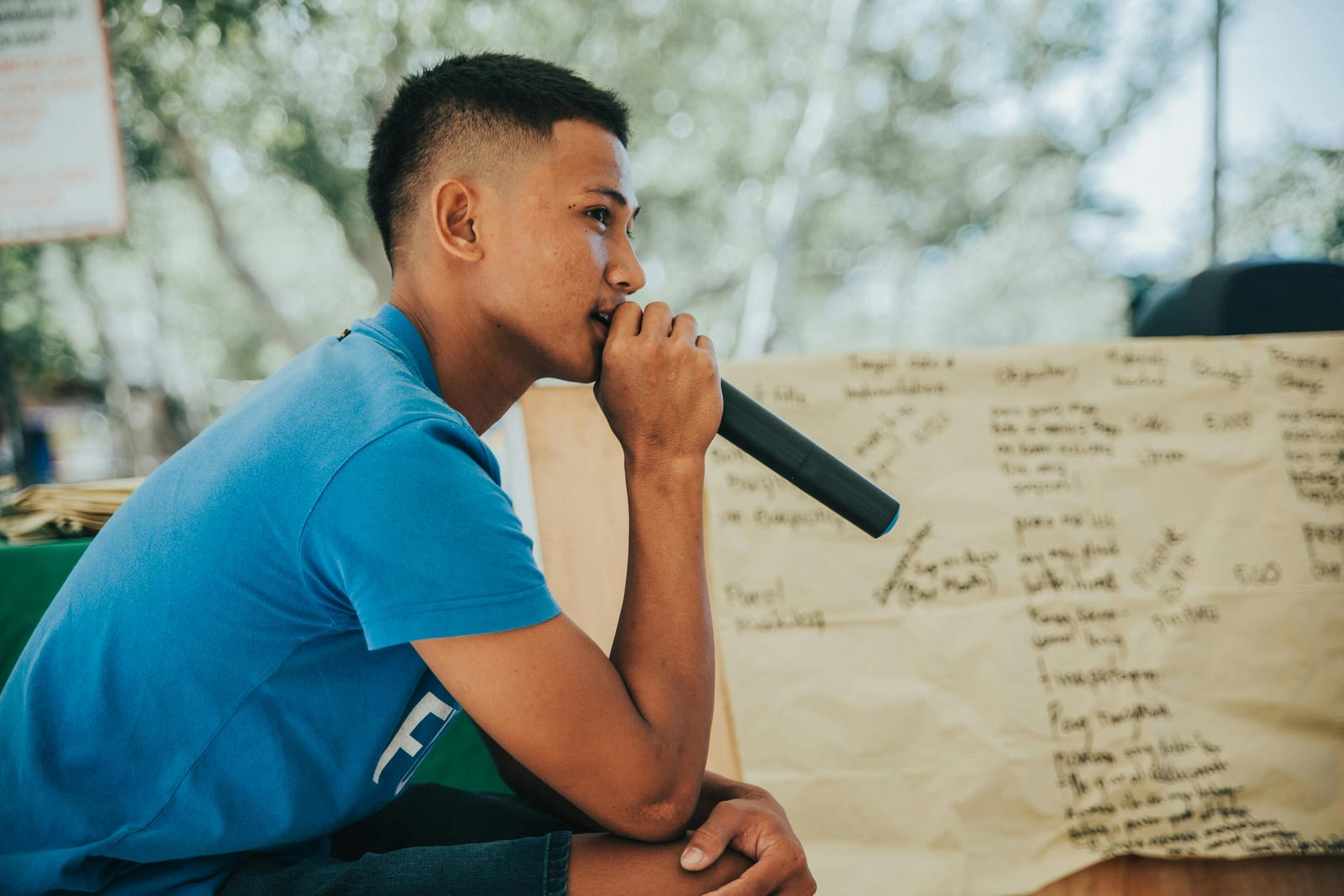 A 24 year old man holds a microphone and talks about his music project